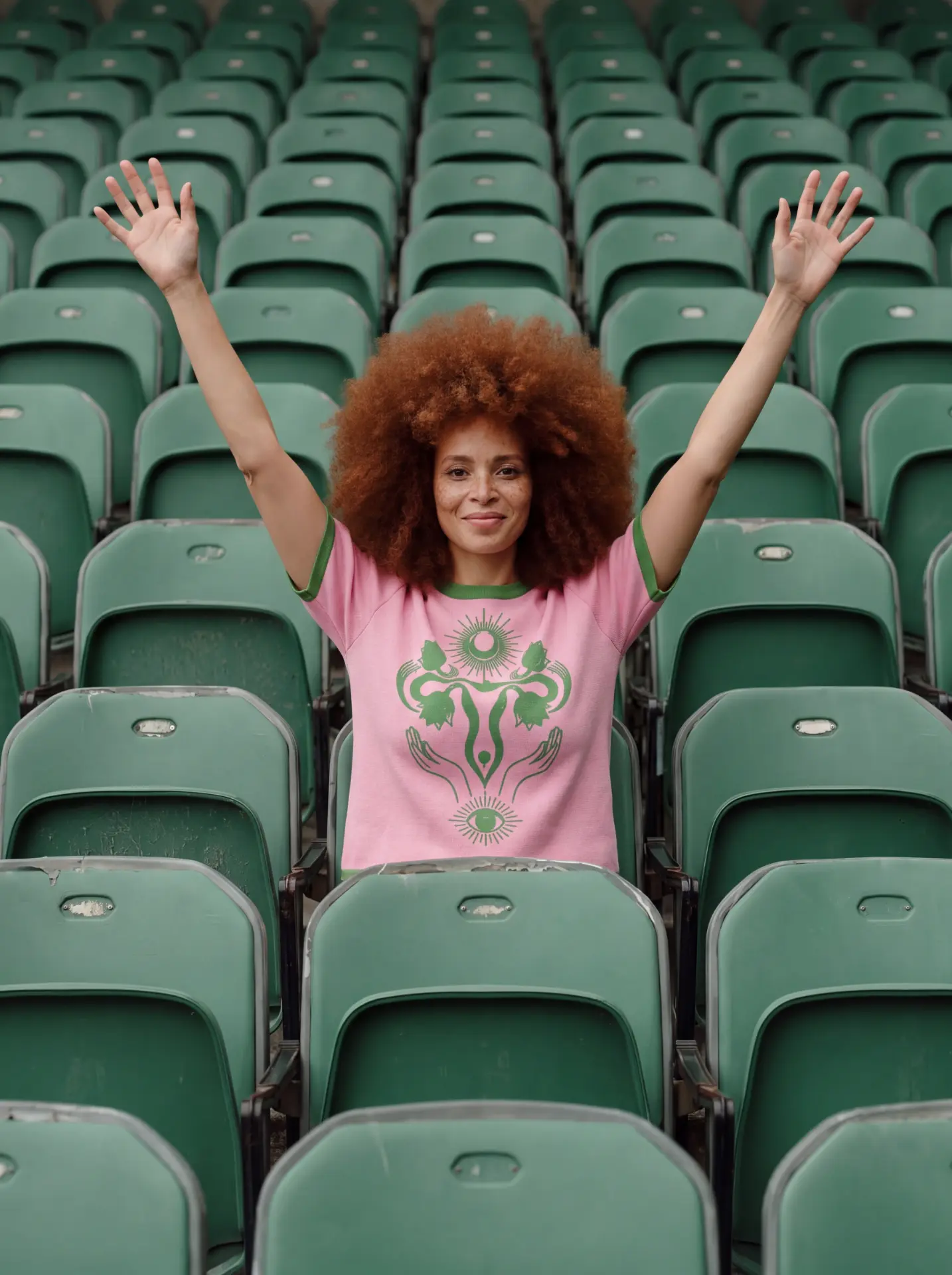 Magic Garden Knit Tee styled in green stadium seats with arms raised